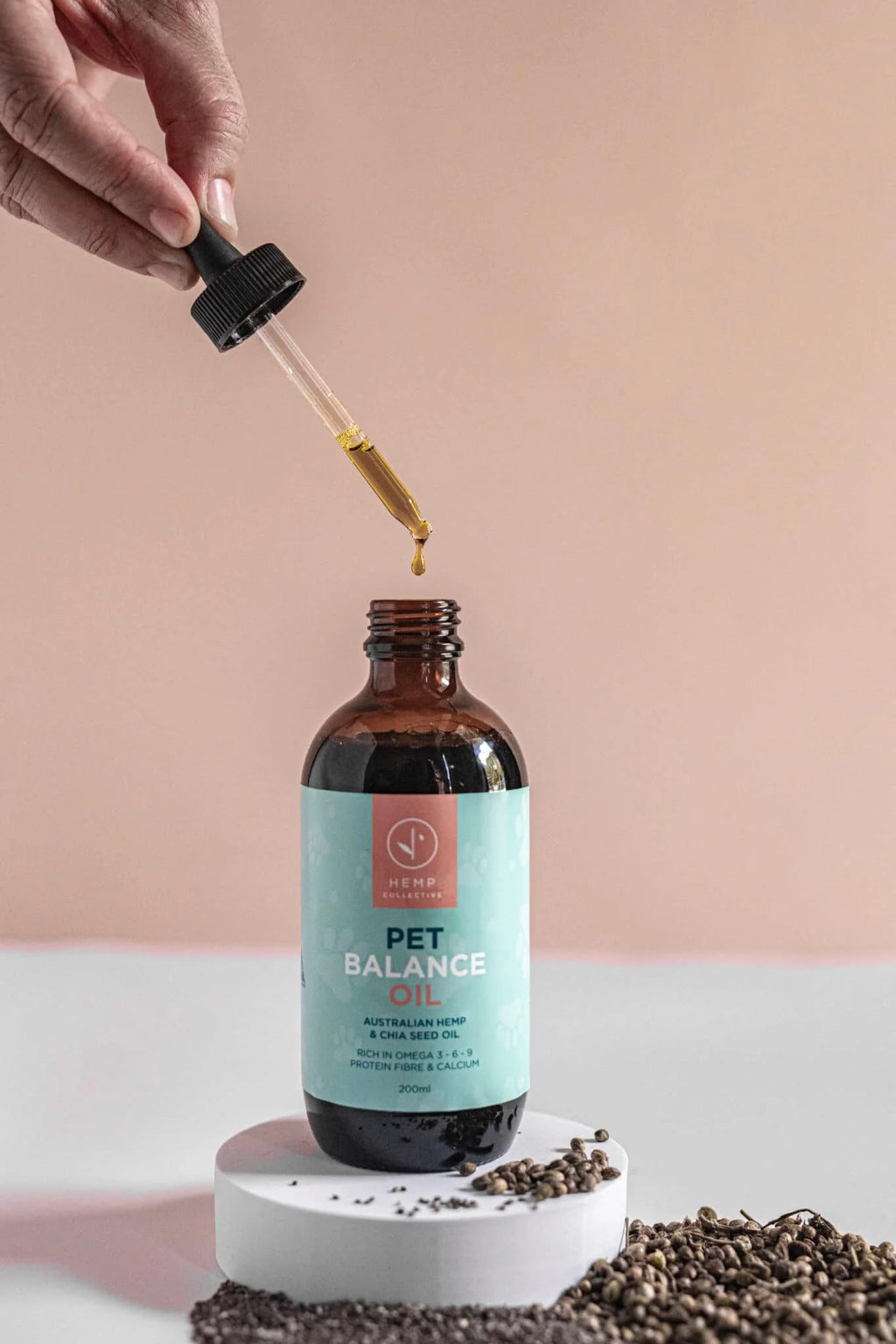 Bottle of 'Pet Balance Oil' with a dropper being used on a pink background