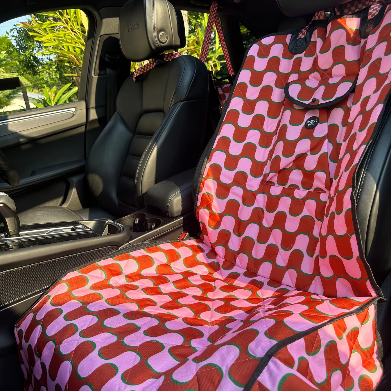 Car seat covers for dogs with a colorful pattern in a vehicle interior.