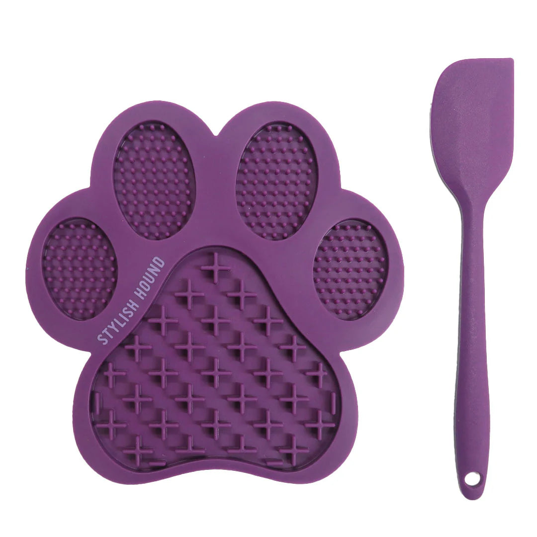 Purple paw-shaped pet lick mat and spatula on a white background