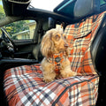 Dog sitting on a plaid car seat cover in a car