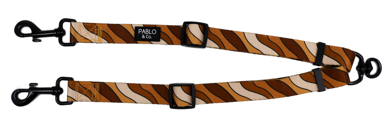 Brown wave print dog leash splitter with black hardware on a white background