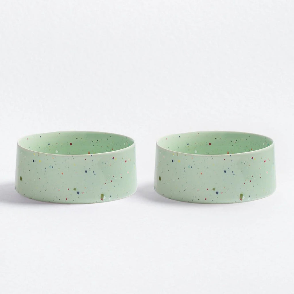 Two green ceramic pet bowls with speckled pattern on a white background