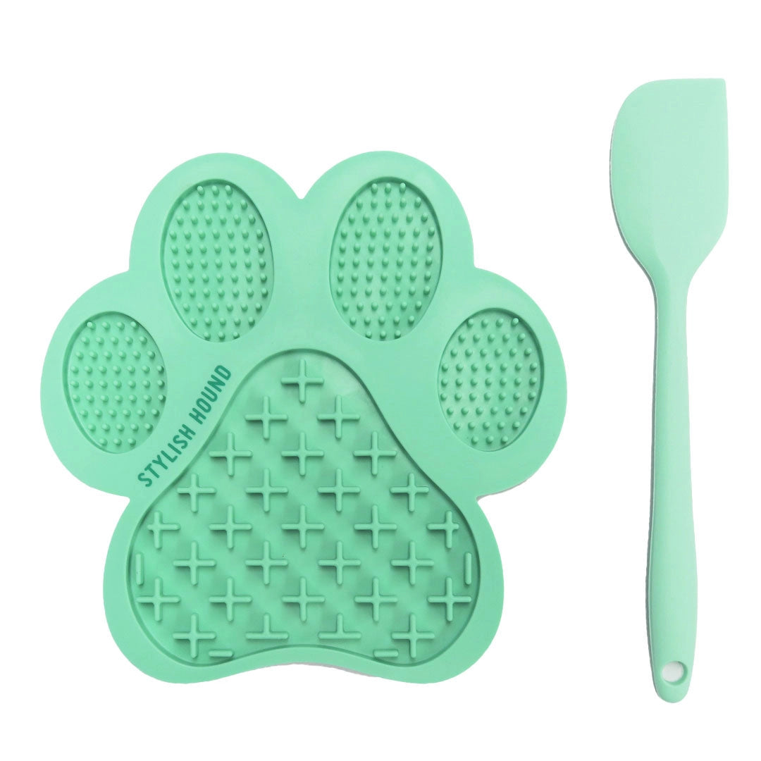Mint green paw-shaped silicone lick mat and spatula on a white background