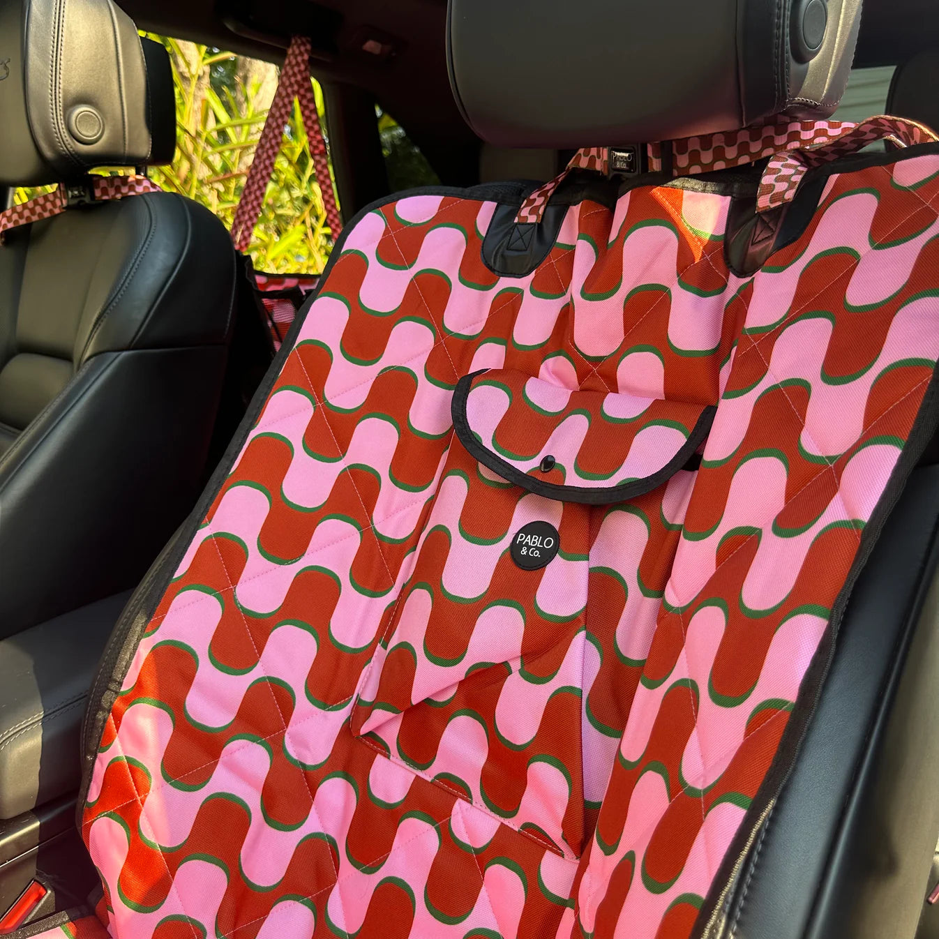 Pink and red patterned car seat cover on a car seat