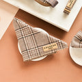 Plaid-patterned dog bandana with 'Cocopup' branding on a brown surface.
