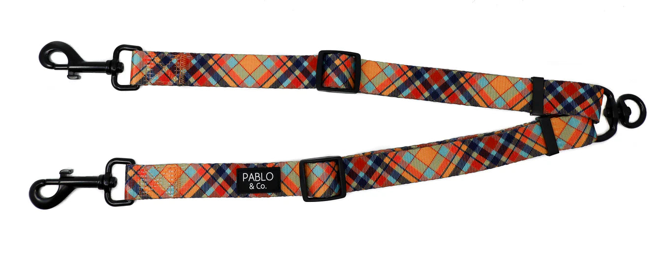 Plaid patterned dog leash splitter with black hardware on a white background